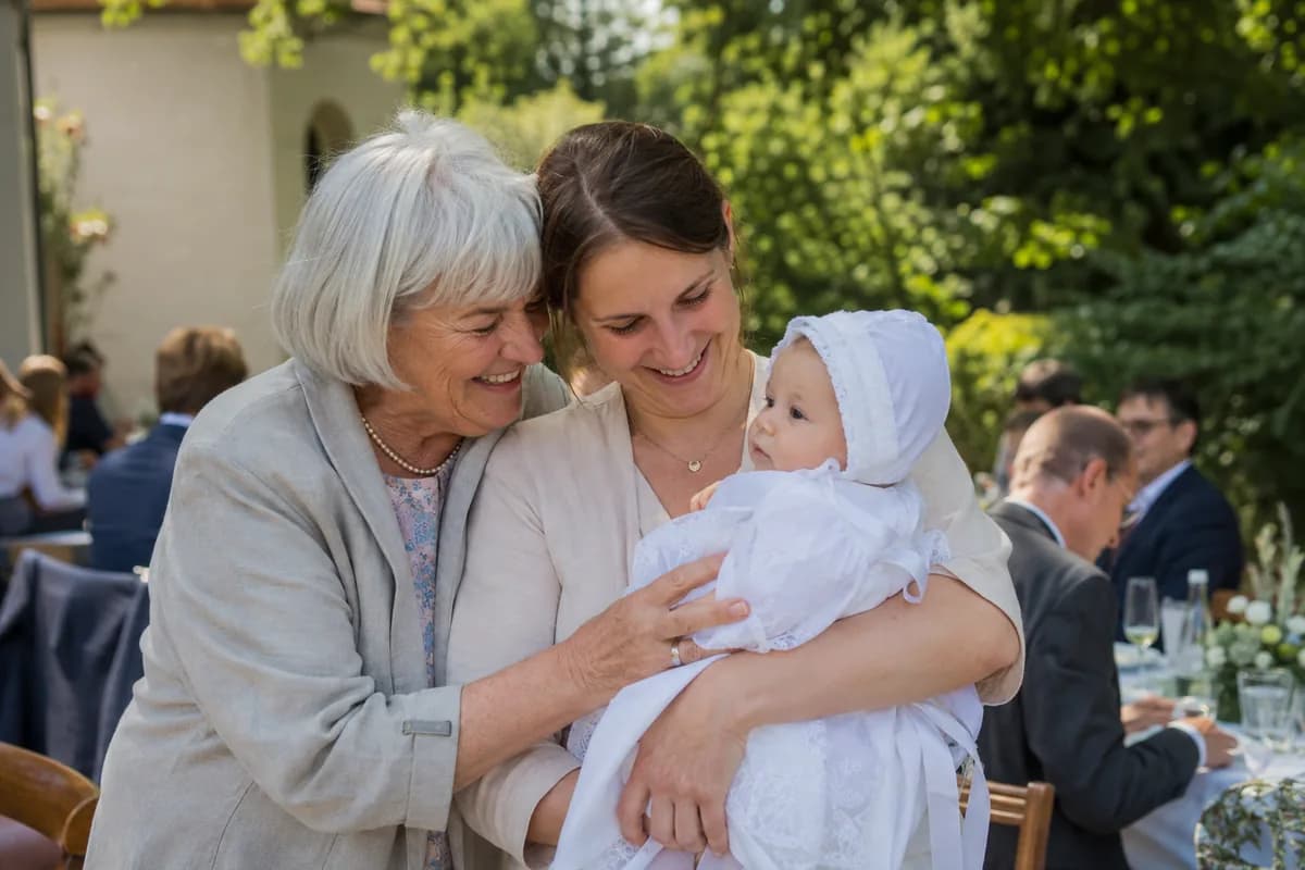 Grandmother hugging mother and baby at a christening celebration