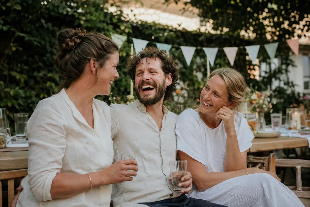 Friends laughing at a birthday table with bunting in the garden