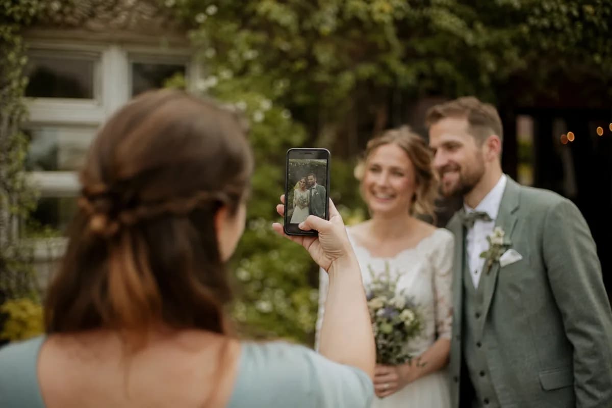 Wedding guest photographing the bride and groom with her phone
